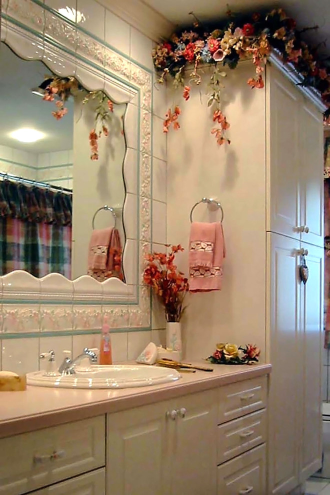 Idée de décoration pour une grande salle de bain tradition pour enfant avec un placard avec porte à panneau surélevé, WC à poser, un mur beige, un lavabo posé, un plan de toilette en marbre, un sol blanc, des portes de placard blanches et un sol en carrelage de céramique.