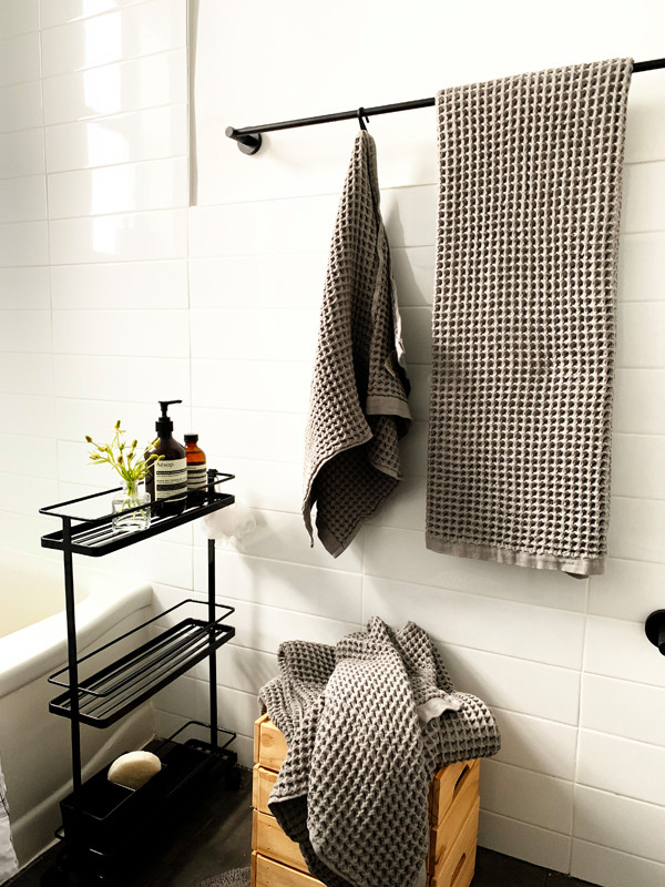 Cette image montre une petite salle de bain nordique avec des portes de placard noires, WC à poser, un carrelage blanc, un carrelage métro, un mur blanc, un sol en carrelage de céramique, un plan vasque et un sol gris.