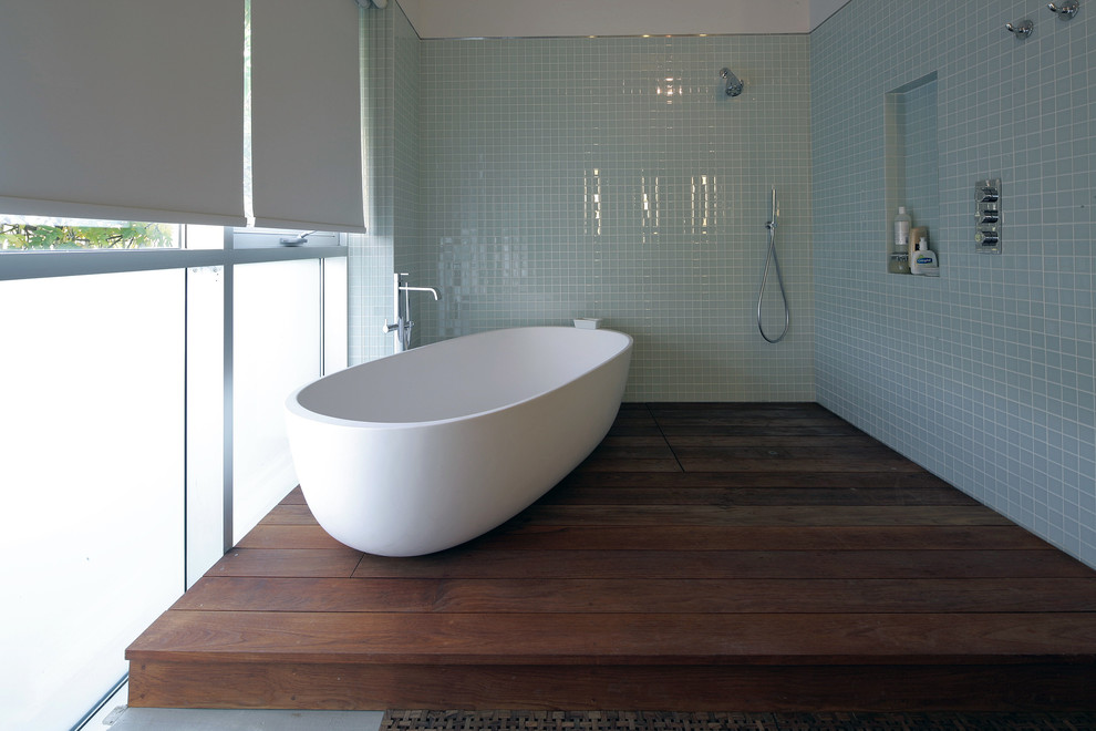 Cette image montre une salle de bain design avec une baignoire indépendante, une douche ouverte, aucune cabine et une fenêtre.