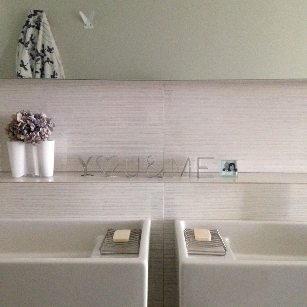 Modern inredning av ett litet en-suite badrum, med släta luckor, grå skåp, ett badkar i en alkov, en dusch i en alkov, en toalettstol med hel cisternkåpa, grå kakel, porslinskakel, grå väggar, klinkergolv i porslin, ett väggmonterat handfat och kaklad bänkskiva