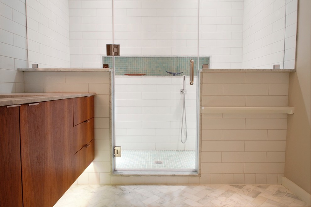 Cette photo montre une grande salle de bain principale chic en bois foncé avec un placard à porte plane, une douche double, WC suspendus, un carrelage blanc, des carreaux de céramique, un mur gris, un sol en marbre, un plan de toilette en marbre et un lavabo encastré.