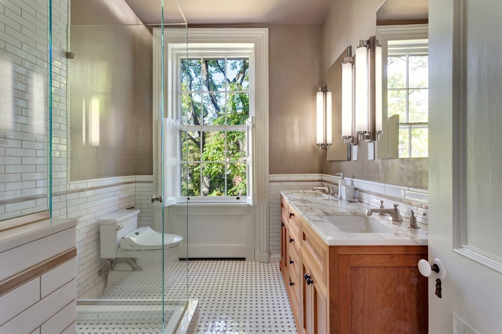Example of a large classic 3/4 subway tile mosaic tile floor corner shower design in New York with shaker cabinets, medium tone wood cabinets, a two-piece toilet, brown walls, an undermount sink and marble countertops
