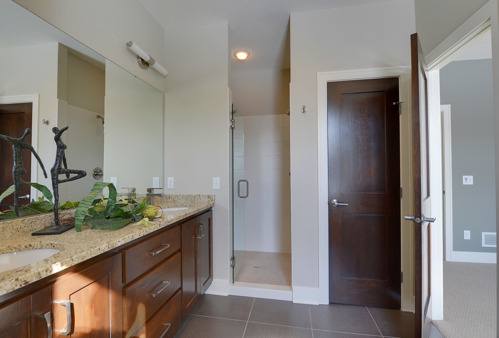 Bild på ett litet funkis en-suite badrum, med ett undermonterad handfat, luckor med infälld panel, skåp i mellenmörkt trä, granitbänkskiva, en dusch i en alkov, en toalettstol med hel cisternkåpa, grå kakel, stenhäll, grå väggar och klinkergolv i porslin