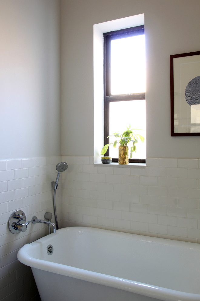 Classic bathroom in New York with a console sink, a claw-foot bath, a corner shower, a wall mounted toilet, white tiles, ceramic tiles, grey walls and porcelain flooring.