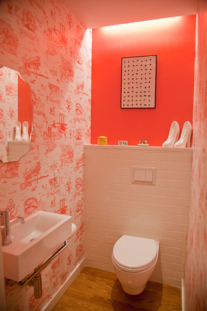 Пример оригинального дизайна: маленький туалет в стиле неоклассика (современная классика) с унитазом-моноблоком, белой плиткой, плиткой кабанчик, красными стенами, светлым паркетным полом и подвесной раковиной для на участке и в саду