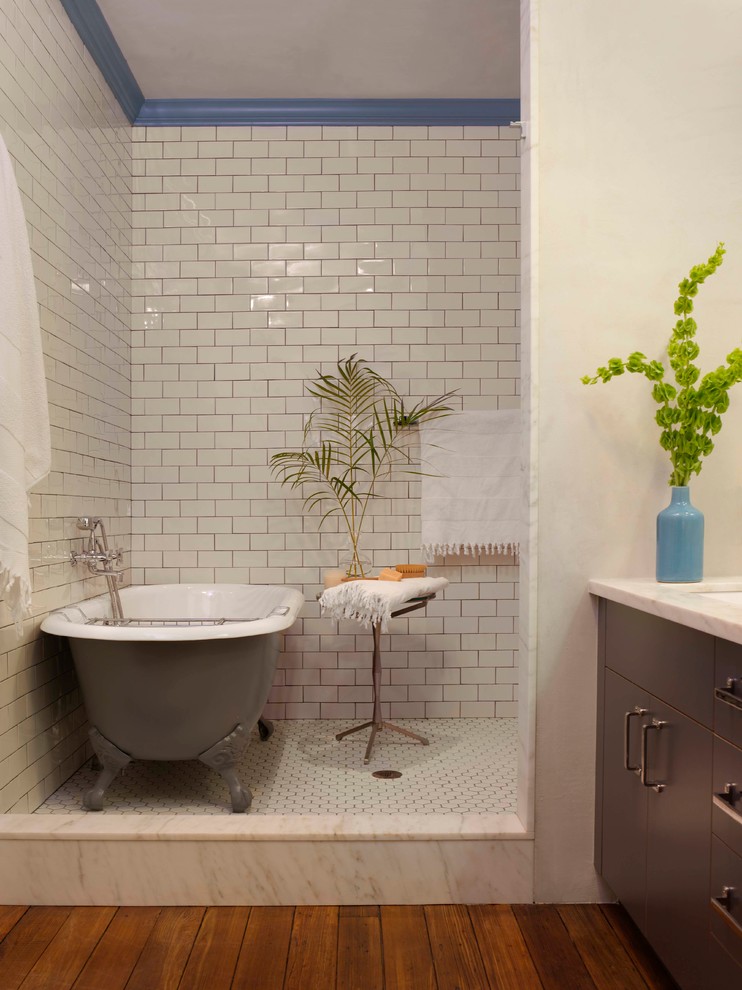 Traditional bathroom in New York with metro tiles, flat-panel cabinets, brown cabinets, a freestanding bath and white tiles.