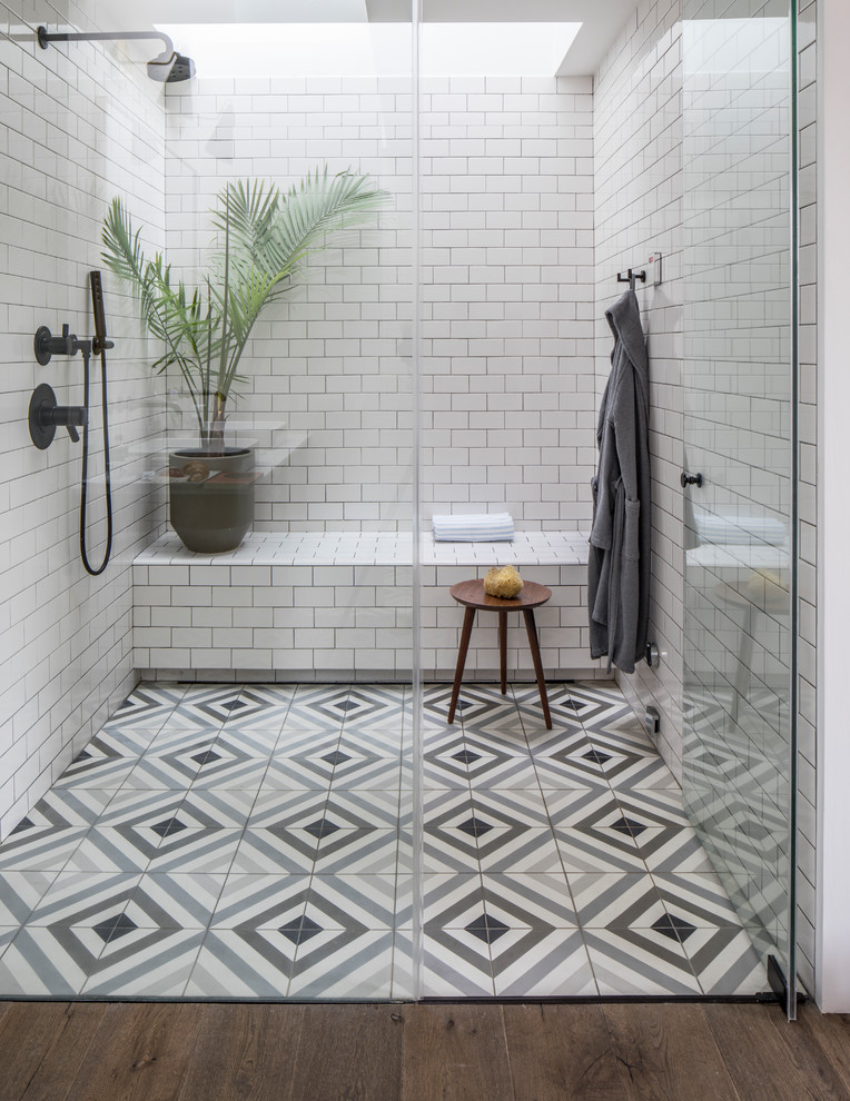 Réalisation d'une salle de bain principale nordique avec une douche à l'italienne, un carrelage métro, un mur blanc, carreaux de ciment au sol, une cabine de douche à porte battante, un carrelage blanc et un sol multicolore.
