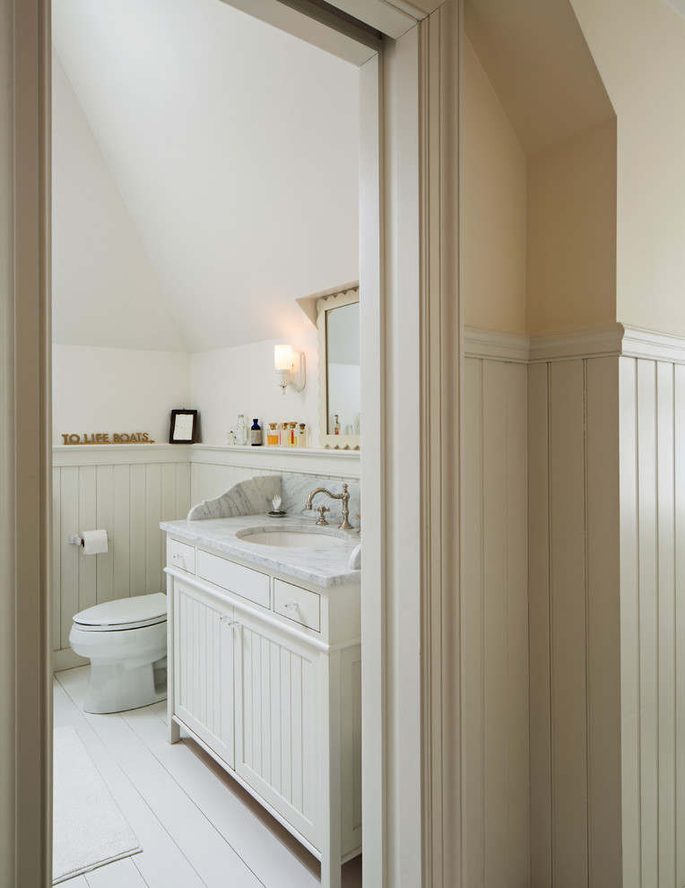 Modelo de cuarto de baño principal romántico pequeño con lavabo tipo consola, armarios estilo shaker, puertas de armario blancas, encimera de mármol, bañera con patas, combinación de ducha y bañera, sanitario de una pieza, paredes blancas y suelo de madera pintada