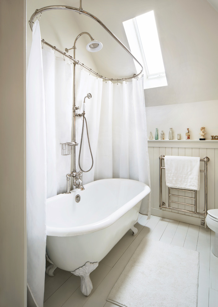 Foto di una stanza da bagno country con vasca con piedi a zampa di leone, vasca/doccia, pareti bianche e pavimento in legno verniciato