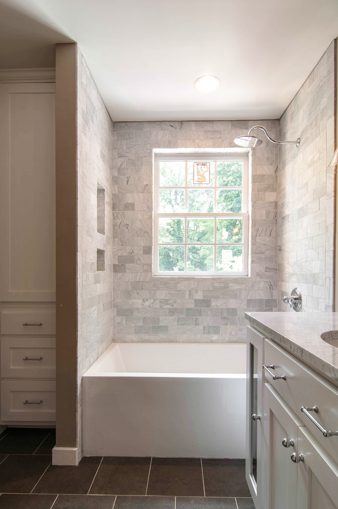 Immagine di una stanza da bagno chic con lavabo sottopiano, ante lisce, ante bianche, top in marmo, vasca/doccia, WC a due pezzi, piastrelle grigie e piastrelle in pietra