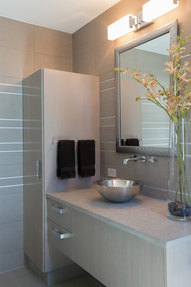 Modern inredning av ett mellanstort badrum, med ett fristående handfat, släta luckor, grå skåp, bänkskiva i kalksten, en öppen dusch, en toalettstol med hel cisternkåpa, grå kakel, porslinskakel, grå väggar och klinkergolv i porslin