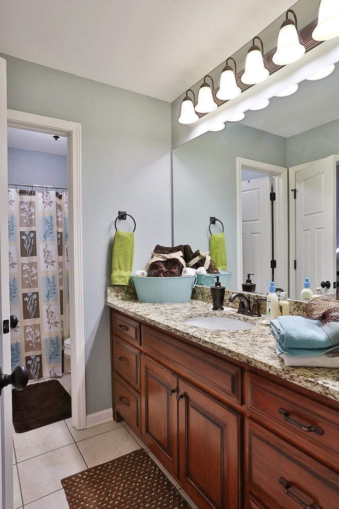 Mittelgroßes Landhausstil Badezimmer mit profilierten Schrankfronten, hellbraunen Holzschränken, Granit-Waschbecken/Waschtisch und weißen Fliesen in Atlanta