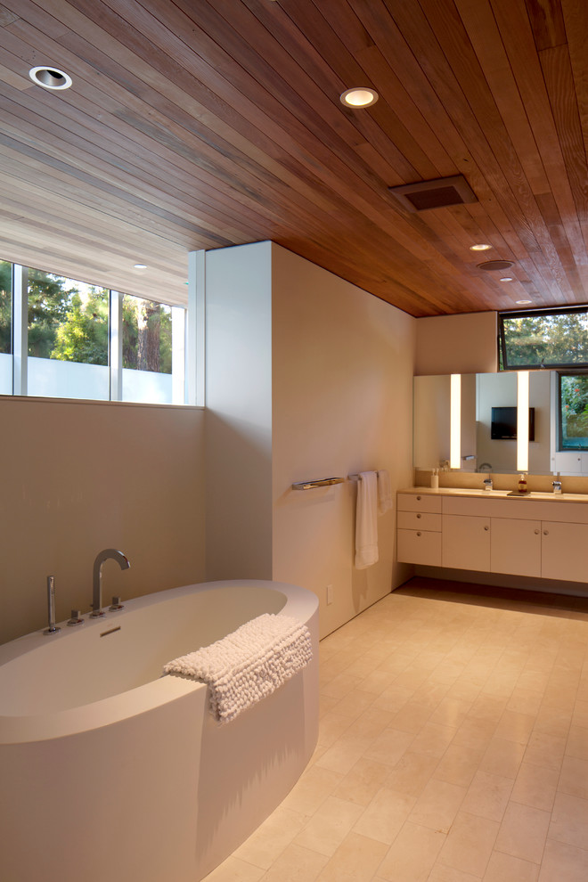 ロサンゼルスにある広いミッドセンチュリースタイルのおしゃれなマスターバスルーム (置き型浴槽、フラットパネル扉のキャビネット、白いキャビネット、白い壁、磁器タイルの床、クオーツストーンの洗面台、白い床) の写真