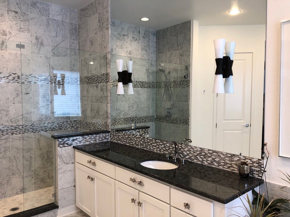 Bathroom - mid-sized contemporary master gray tile and stone tile marble floor and gray floor bathroom idea in Denver with shaker cabinets, white cabinets, a one-piece toilet, white walls, an undermount sink, granite countertops, a hinged shower door and black countertops