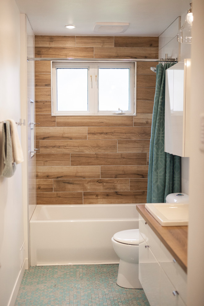 Bild på ett litet funkis en-suite badrum, med släta luckor, vita skåp, ett badkar i en alkov, en dusch/badkar-kombination, en toalettstol med hel cisternkåpa, brun kakel, keramikplattor, vita väggar, mosaikgolv, laminatbänkskiva, turkost golv och dusch med duschdraperi