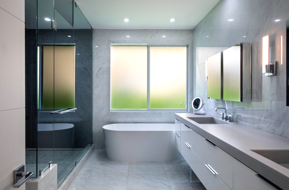 На фото: главная ванная комната в современном стиле с плоскими фасадами, серыми фасадами, отдельно стоящей ванной, душем в нише, черной плиткой, плиткой мозаикой, серыми стенами, мраморным полом, монолитной раковиной, столешницей из бетона, серым полом, душем с распашными дверями и серой столешницей
