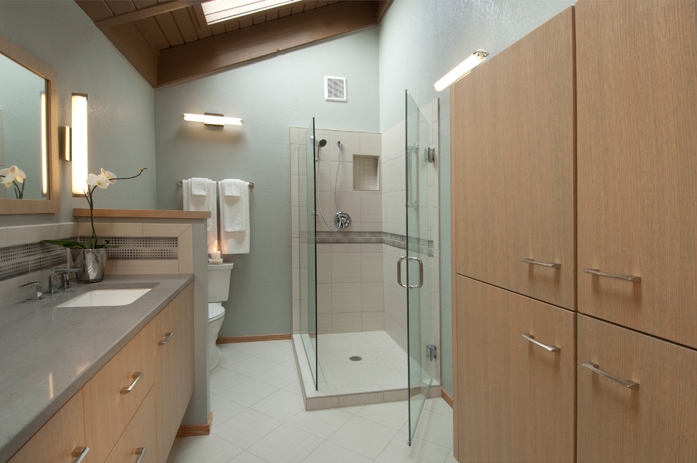 This is an example of a medium sized contemporary ensuite bathroom in Seattle with a submerged sink, flat-panel cabinets, medium wood cabinets, engineered stone worktops, a corner shower, a one-piece toilet, beige tiles, porcelain tiles, grey walls and porcelain flooring.