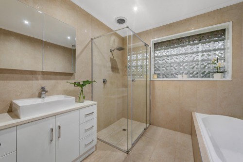 Idéer för att renovera ett mellanstort funkis vit vitt en-suite badrum, med släta luckor, vita skåp, ett undermonterat badkar, beige kakel, porslinskakel, beige väggar, klinkergolv i porslin, bänkskiva i kvarts, beiget golv och dusch med gångjärnsdörr