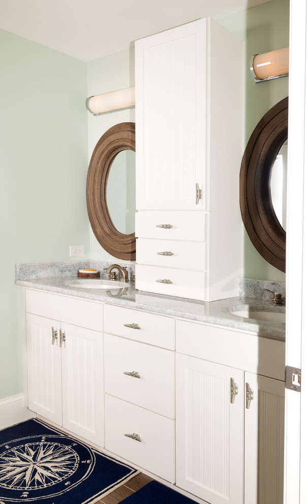 Example of a beach style medium tone wood floor bathroom design in Milwaukee with louvered cabinets, white cabinets, green walls, an undermount sink and marble countertops