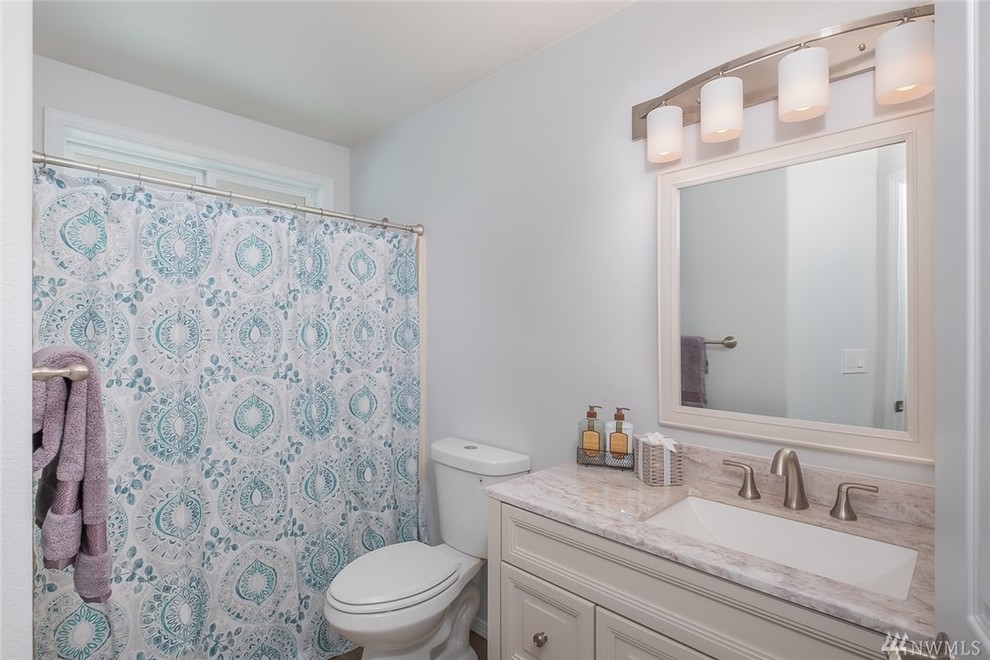 Inredning av ett modernt mellanstort beige beige badrum, med luckor med infälld panel, vita skåp, en dusch/badkar-kombination, grå väggar, ett nedsänkt handfat, bänkskiva i kvartsit och dusch med duschdraperi