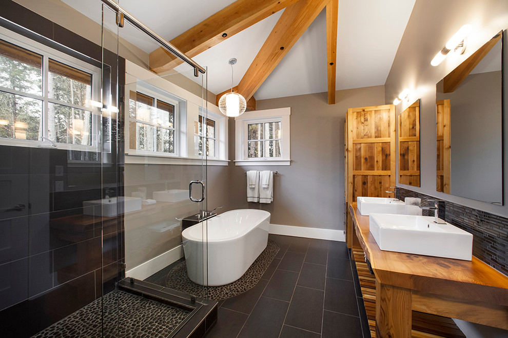 Exemple d'une salle de bain tendance en bois brun avec une vasque, une baignoire indépendante, une douche d'angle, un carrelage noir, un placard sans porte, un sol noir, un plan de toilette en bois et un plan de toilette marron.