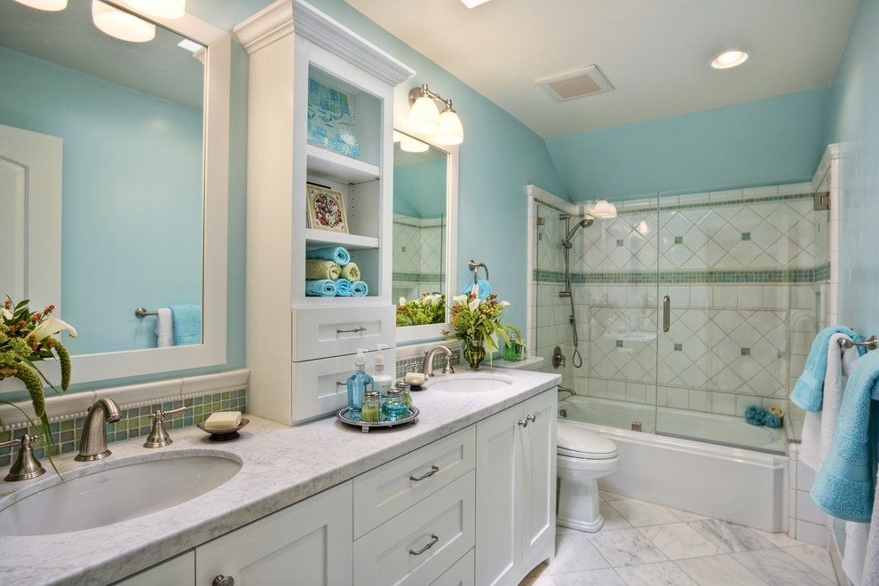 На фото: ванная комната среднего размера в классическом стиле с врезной раковиной, фасадами в стиле шейкер, белыми фасадами, мраморной столешницей, душем над ванной, белой плиткой, керамогранитной плиткой, синими стенами, полом из керамогранита и накладной ванной