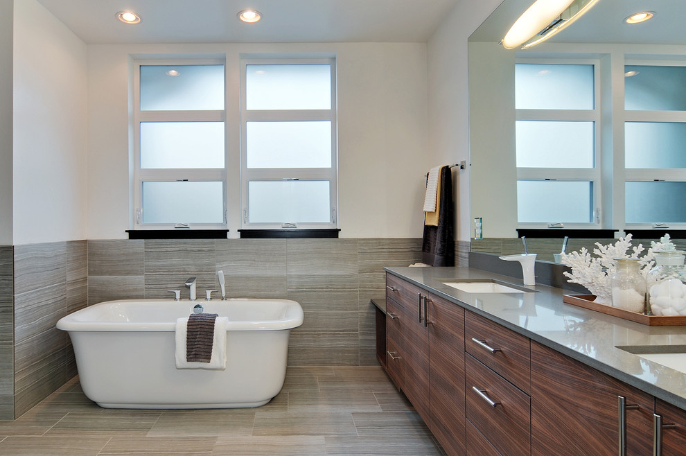 Large modern ensuite bathroom in Seattle with flat-panel cabinets, brown cabinets, a freestanding bath, grey tiles, ceramic tiles, white walls, ceramic flooring, a submerged sink, engineered stone worktops and grey worktops.