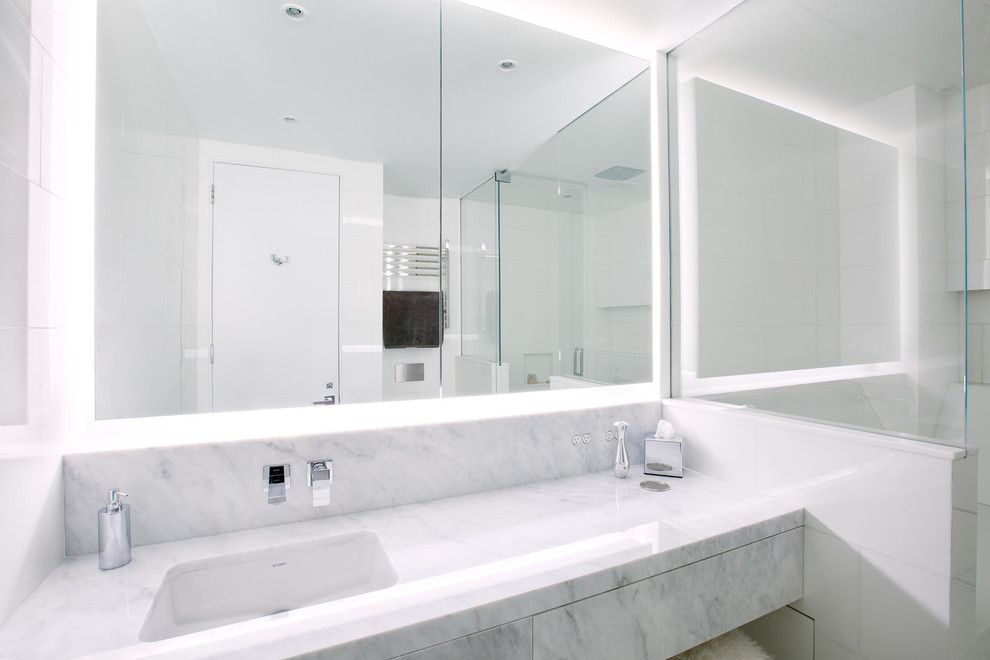 Стильный дизайн: большая главная ванная комната в стиле модернизм с ванной в нише, душем над ванной, белой плиткой, керамогранитной плиткой, белыми стенами, полом из керамогранита, врезной раковиной, мраморной столешницей, белым полом, душем с распашными дверями и серой столешницей - последний тренд