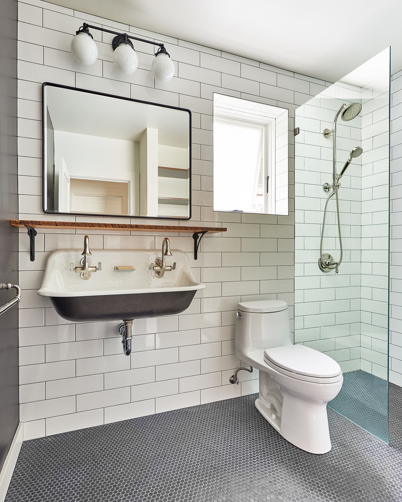 Bild på ett vintage badrum med dusch, med en kantlös dusch, en toalettstol med hel cisternkåpa, vit kakel, tunnelbanekakel, vita väggar, mosaikgolv, ett avlångt handfat, grått golv och med dusch som är öppen