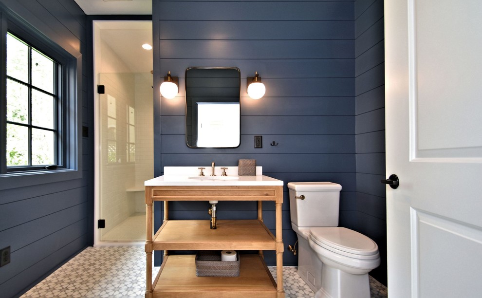Diseño de cuarto de baño marinero con armarios abiertos, puertas de armario de madera oscura, ducha esquinera, paredes azules, lavabo bajoencimera, suelo multicolor y encimeras blancas