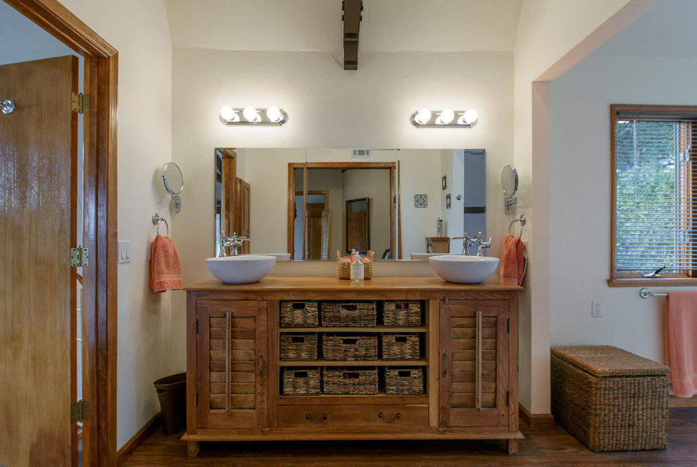 This is an example of a mediterranean ensuite bathroom in San Luis Obispo with medium wood cabinets, white walls, medium hardwood flooring, a vessel sink, wooden worktops, brown floors and louvered cabinets.