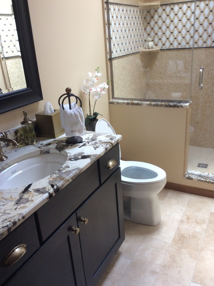 Example of a mid-sized classic 3/4 beige tile, black and white tile, multicolored tile and stone slab ceramic tile alcove shower design in Columbus with recessed-panel cabinets, dark wood cabinets, a two-piece toilet, beige walls, an undermount sink and marble countertops