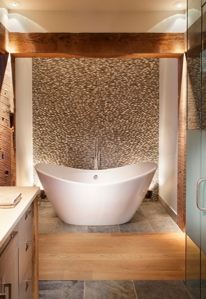 Exempel på ett rustikt badrum, med släta luckor, skåp i mellenmörkt trä, ett fristående badkar, kakel i småsten, vita väggar, mellanmörkt trägolv och brun kakel