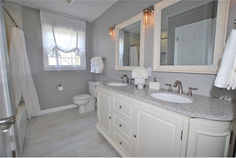 Inspiration for a medium sized classic bathroom in Indianapolis with freestanding cabinets, beige cabinets, an alcove bath, a shower/bath combination, a two-piece toilet, grey tiles, ceramic tiles, grey walls, ceramic flooring, a submerged sink, marble worktops, grey floors and a shower curtain.
