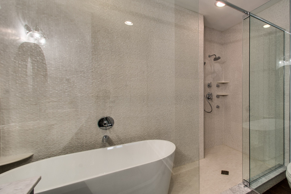 Inredning av ett klassiskt mellanstort badrum med dusch, med luckor med infälld panel, skåp i slitet trä, ett fristående badkar, våtrum, grå kakel, kakel i småsten, beige väggar, mellanmörkt trägolv, ett fristående handfat, marmorbänkskiva, brunt golv och dusch med gångjärnsdörr