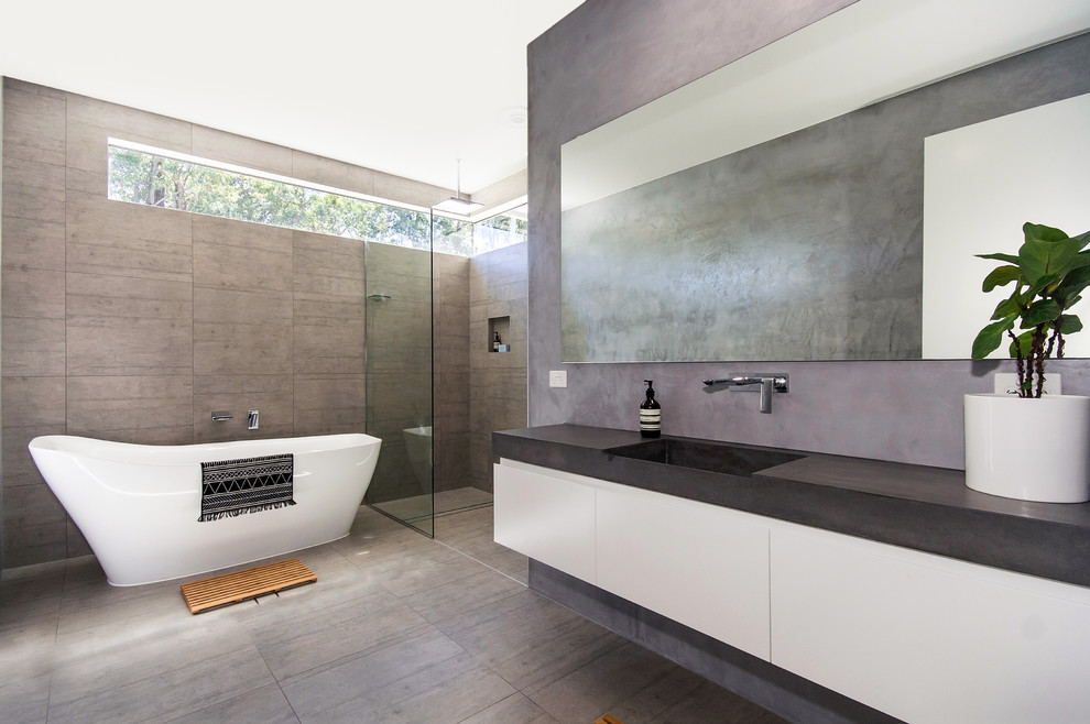 Idées déco pour une grande salle de bain principale moderne avec des portes de placard blanches, une baignoire indépendante, une douche d'angle, un carrelage gris, des carreaux de porcelaine, un mur gris, un sol en carrelage de porcelaine, un lavabo intégré et un plan de toilette en béton.
