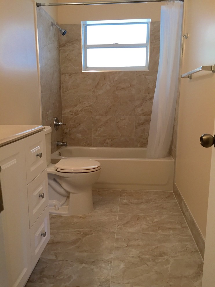 Immagine di una stanza da bagno minimal di medie dimensioni con ante bianche, vasca da incasso, WC a due pezzi, piastrelle beige, piastrelle in ceramica, pareti beige, pavimento con piastrelle in ceramica e lavabo sottopiano