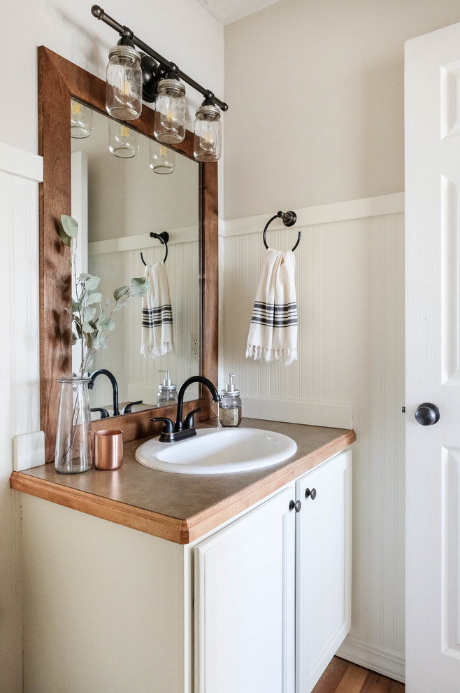 Lantlig inredning av ett mellanstort beige beige badrum med dusch, med luckor med upphöjd panel, vita skåp, vit kakel och laminatbänkskiva