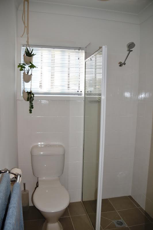 Bild på ett litet funkis badrum, med träbänkskiva, en dusch i en alkov, en toalettstol med hel cisternkåpa, vit kakel, keramikplattor, vita väggar och klinkergolv i keramik