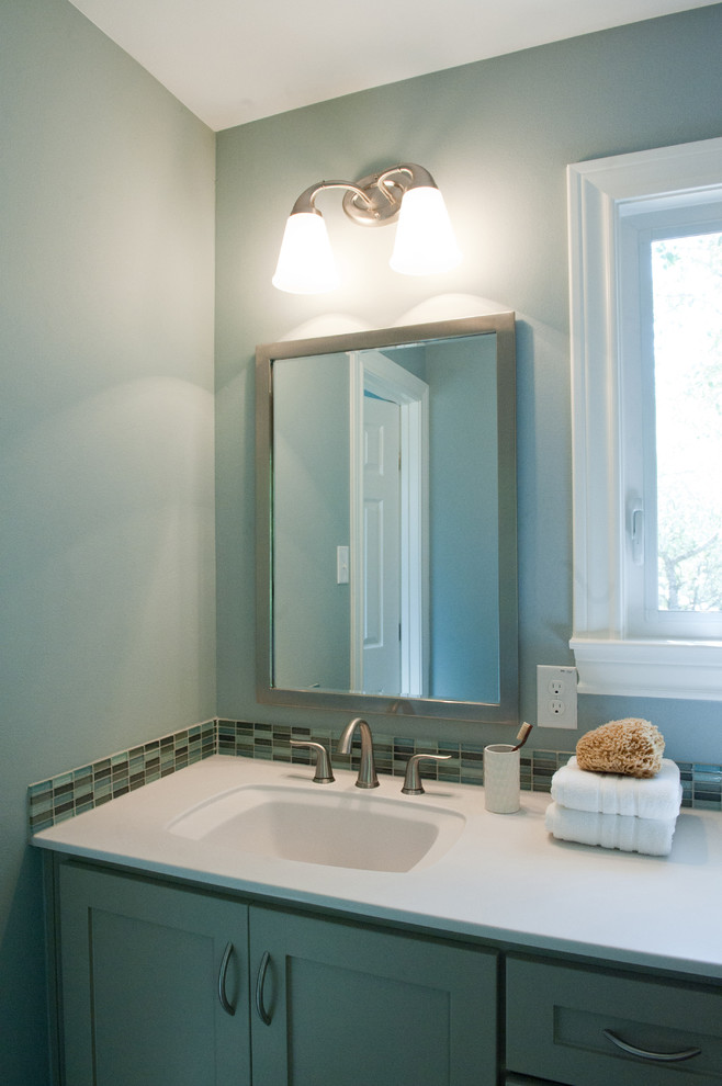 Esempio di una stanza da bagno per bambini moderna di medie dimensioni con lavabo integrato, ante in stile shaker, ante grigie, top in superficie solida, vasca ad alcova, vasca/doccia, piastrelle blu, piastrelle di vetro, pareti blu e pavimento con piastrelle in ceramica