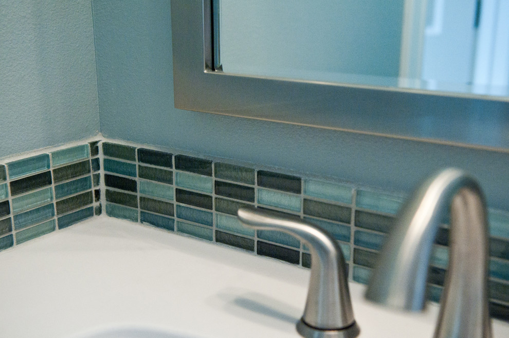 Foto på ett mellanstort funkis badrum för barn, med ett integrerad handfat, skåp i shakerstil, grå skåp, bänkskiva i akrylsten, ett badkar i en alkov, en dusch/badkar-kombination, blå kakel, glaskakel, blå väggar och klinkergolv i keramik