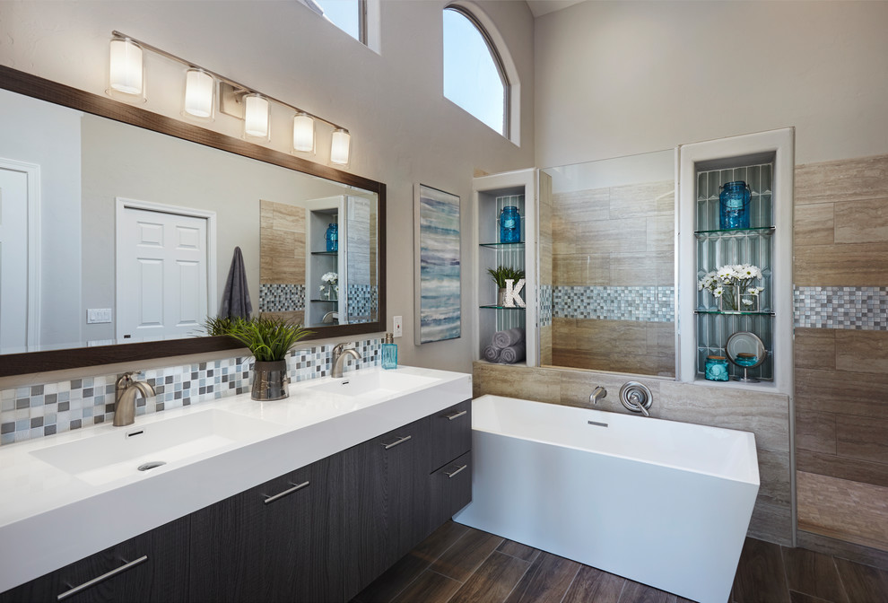 На фото: главная ванная комната в современном стиле с плоскими фасадами, темными деревянными фасадами, отдельно стоящей ванной, бежевой плиткой, бежевыми стенами, монолитной раковиной, коричневым полом и белой столешницей