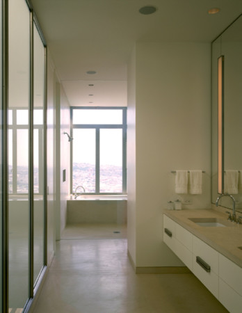 Cette image montre une salle de bain minimaliste de taille moyenne avec un lavabo encastré, un placard à porte plane, des portes de placard blanches, un plan de toilette en calcaire, une baignoire encastrée, une douche ouverte, WC à poser, un carrelage beige, des dalles de pierre, un mur blanc et un sol en calcaire.