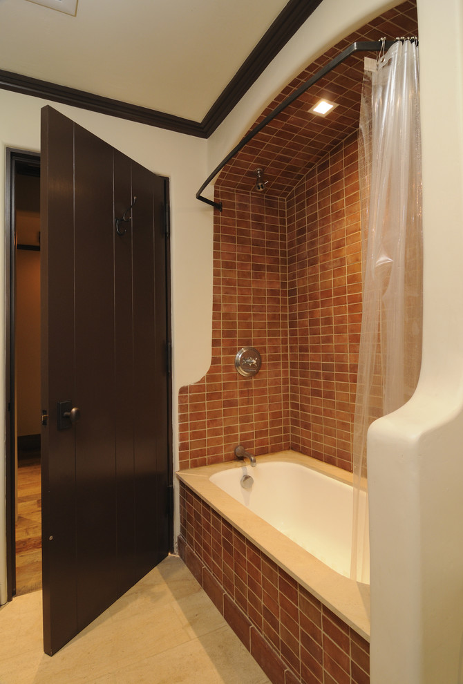Immagine di una stanza da bagno mediterranea con vasca ad alcova e piastrelle marroni
