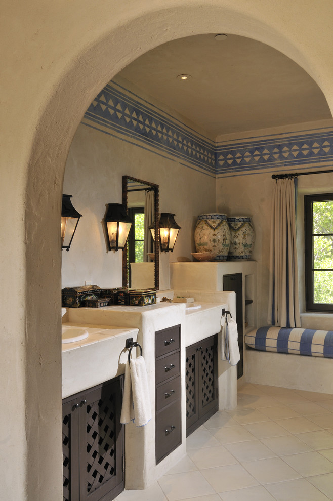 Immagine di una stanza da bagno american style con lavabo da incasso, ante in legno bruno, top piastrellato e piastrelle beige