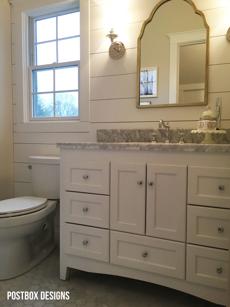 Cette photo montre une petite salle d'eau nature avec un placard à porte shaker, des portes de placard blanches, un mur jaune, un sol en marbre, un lavabo posé et un plan de toilette en marbre.