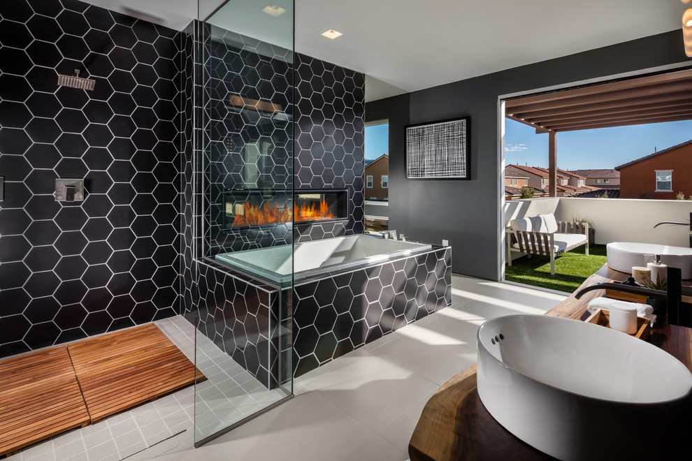 Modelo de cuarto de baño contemporáneo con ducha a ras de suelo, paredes grises, lavabo sobreencimera, encimera de madera y ducha abierta