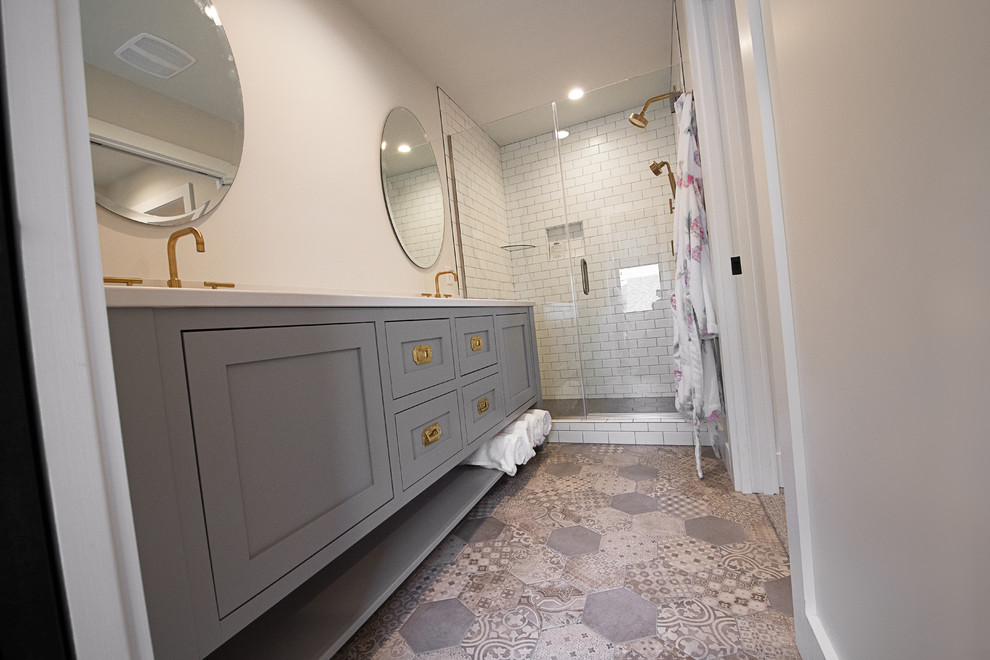 Diseño de cuarto de baño principal clásico renovado de tamaño medio con armarios tipo mueble, puertas de armario grises, ducha empotrada, sanitario de dos piezas, paredes blancas, suelo de azulejos de cemento, lavabo bajoencimera y suelo gris
