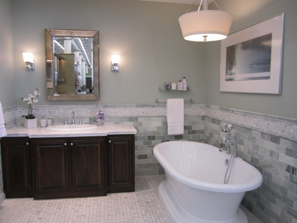 Exemple d'une salle de bain principale chic en bois foncé de taille moyenne avec un placard avec porte à panneau surélevé, une baignoire indépendante, un carrelage vert, un carrelage de pierre, un mur gris, un sol en marbre, un lavabo posé, un plan de toilette en marbre, un sol gris et un plan de toilette blanc.