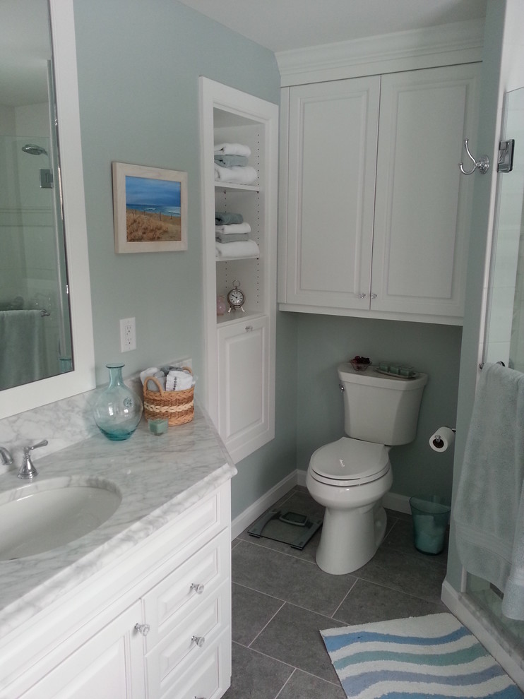 Example of a classic master white tile and ceramic tile porcelain tile corner shower design in Bridgeport with an undermount sink, raised-panel cabinets, white cabinets, marble countertops, a two-piece toilet and gray walls